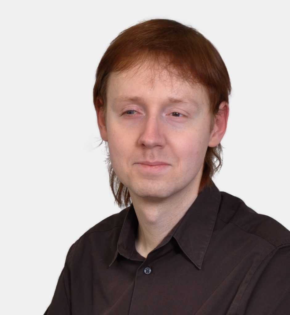 Mann mit längeren roten Haaren und braunem Hemd