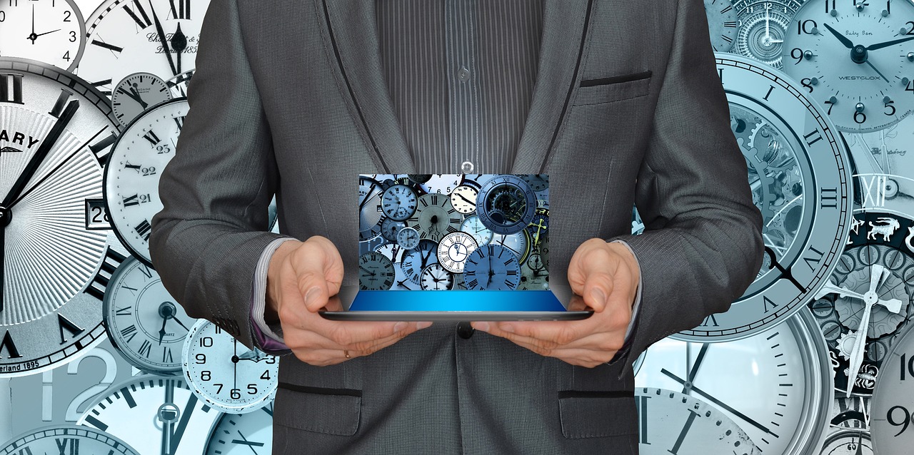 Mann vor Collage aus Uhren hält einen Laptop mit Uhren als Hintergrund
